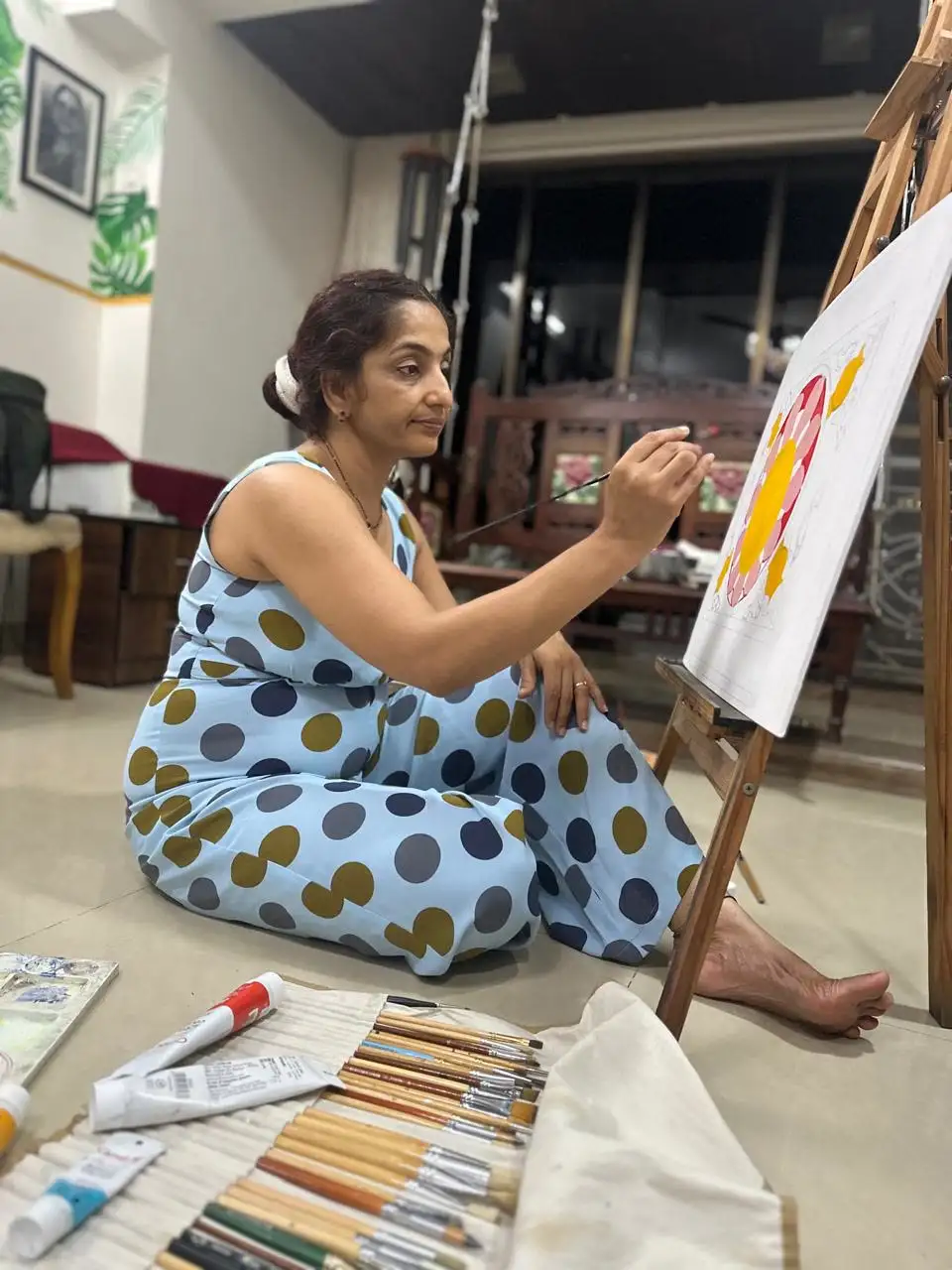Vibhuti Mehta seated on the studio floor, painting a lotus in progress