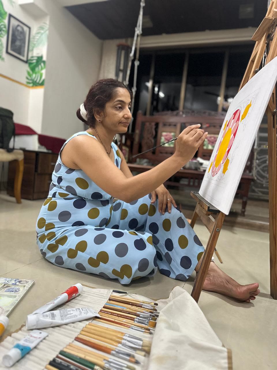 Vibhuti Mehta seated on the studio floor, painting a lotus in progress